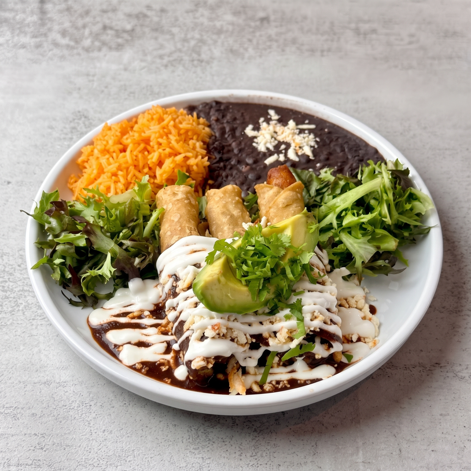 Mexican-inspired plate with orange rice, black beans, taquitos, salad greens, avocado, cilantro, and creamy sauce.